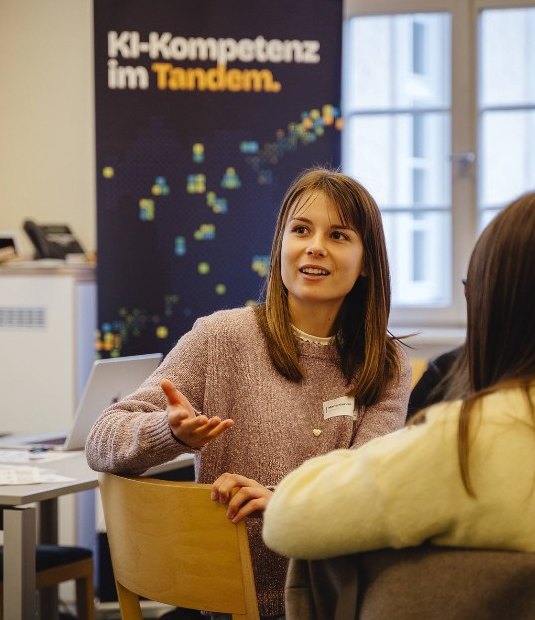 Diskussion vor dem Banner „KI-Kompetenz im Tandem“