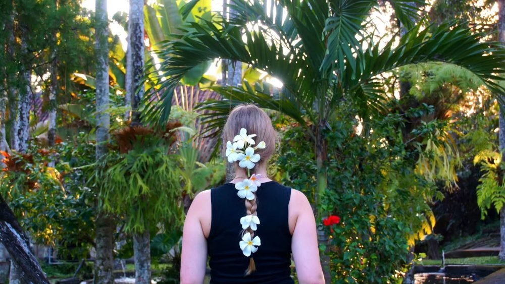 Amelie von hinten mit Blüten im Haar zwischen Palmen